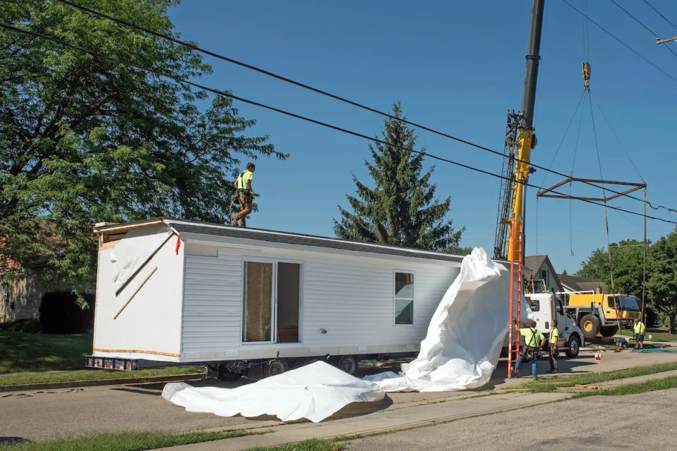 White modular home being installed on a lot.